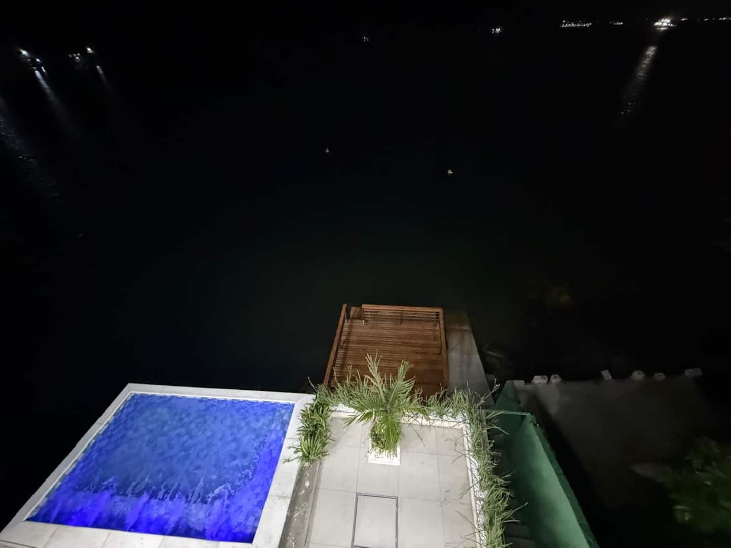 Piscina iluminada à noite de frente para o mar na Casa Ponta da Ilha